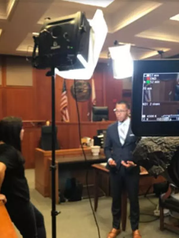 A dapper gentleman in a two piece suit, getting interviewed in a courtroom